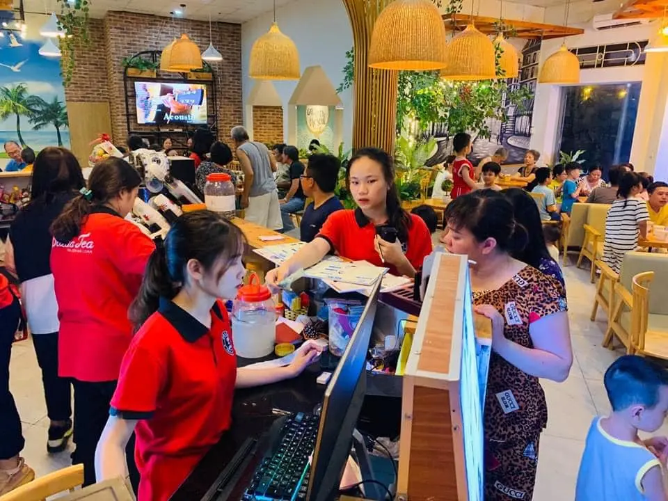 Hình ảnh nhân viên quán trà sữa Pozaa tea đang bán hàng cho khách.