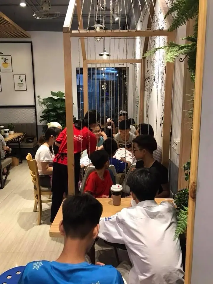 Hình ảnh nhân viên quán trà sữa Pozaa Tea đang phục vụ khách hàng.